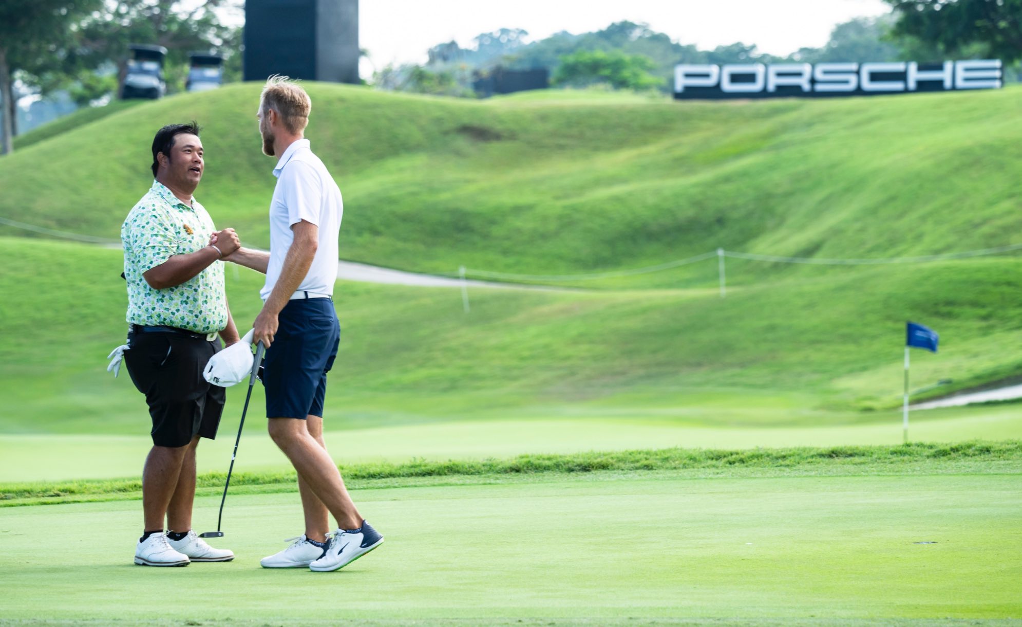 golfers Jesper Svensson and Aphibarnrat shaking hands at the Porsche Singapore Classic