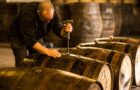 Male worker opening wooden whisky cask in whisky distillery in Scotland